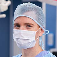 A man in surgical mask and blue scrubs.