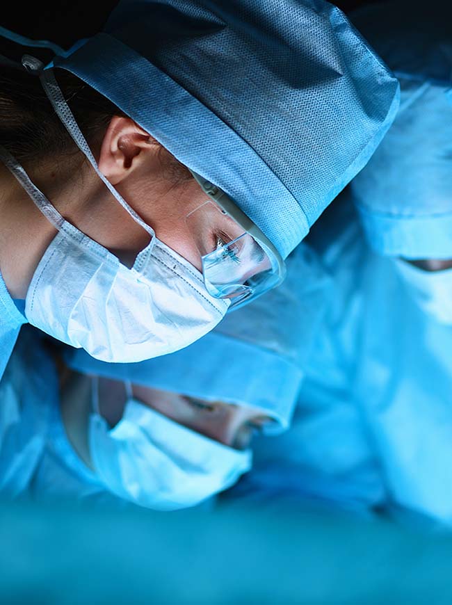 A surgeon is wearing surgical masks while looking down.