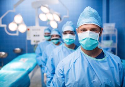 A group of doctors in blue gowns and masks.